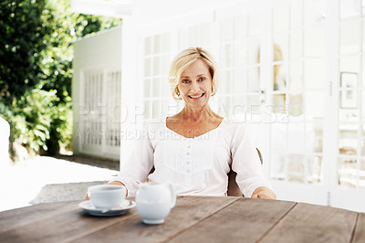 Buy stock photo An attractive mature woman relaxing outside her home with a cup of coffee - portrait