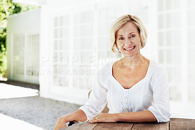 Buy stock photo An attractive mature woman relaxing outside her home and smiling at the camera