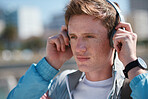 Portrait young redhead man wearing headphones listening to music on waterfront beach looking confident teenager summertime fashion