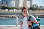 Portrait young redhead man wearing headphones listening to music on waterfront beach looking confident teenager summertime fashion