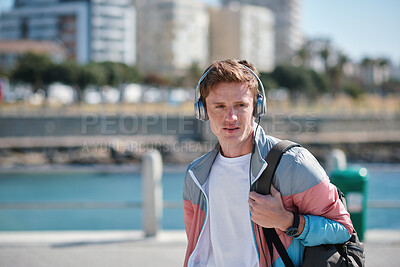 Buy stock photo Headphones, beach and man on holiday with listening to music, playlist or radio with travel. Promenade, audio tech and male person streaming album by ocean on summer vacation, getaway or weekend trip