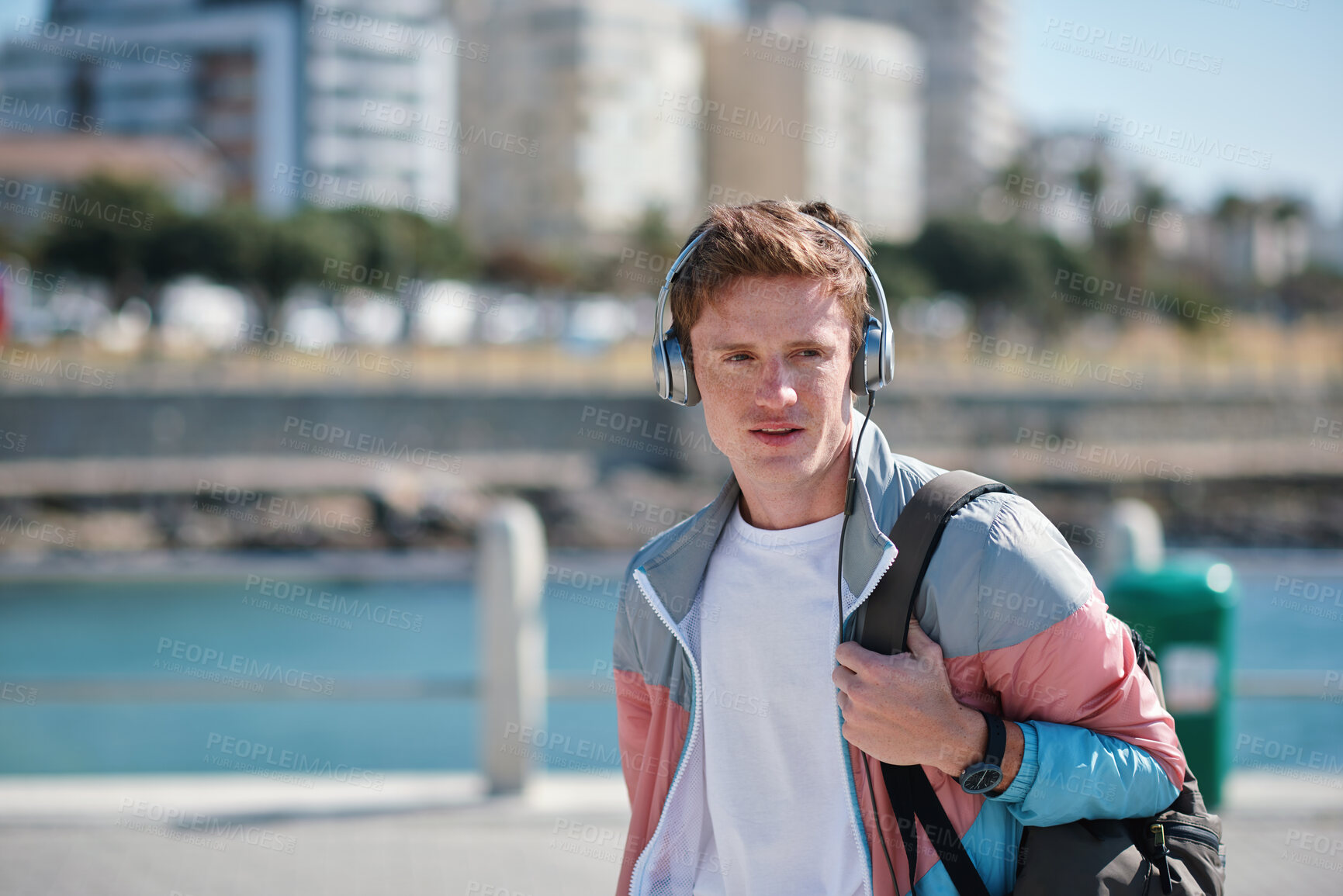 Buy stock photo Headphones, beach and man on holiday with listening to music, playlist or radio with travel. Promenade, audio tech and male person streaming album by ocean on summer vacation, getaway or weekend trip