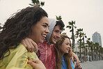 Three friends smiling enjoying view wearing ponchos in the rain having fun at the seaside
