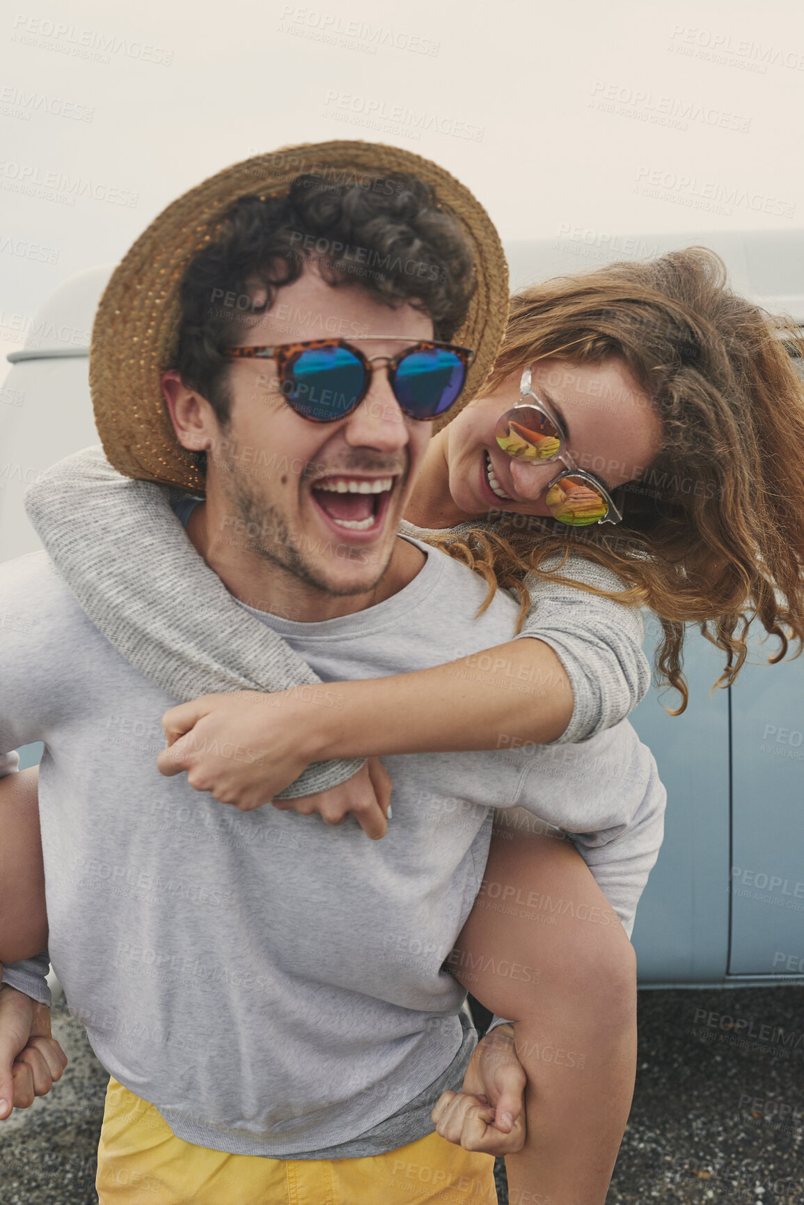 Buy stock photo Couple, happy and piggy back with car for road trip with sunglasses, embrace and connection on vacation. People, partner and relationship on summer getaway, playful and hug with vehicle on holiday