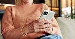 Typing, online and hands with phone in lounge, texting or communication with contact on social media. Scroll, message and mature person with mobile, network and chatting on website with tech in house