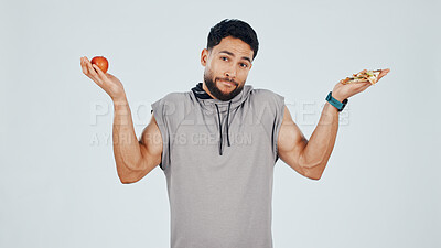Buy stock photo Portrait, apple and man with pizza, decision and weight management for fitness goals. Confused, food or athlete on studio background with shrug, healthy eating or nutrition selection in balanced diet