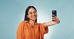 Happy, woman and student with selfie in studio for memory, social media or college blog. Phone, education and female person with photography picture for university about us by blue background.
