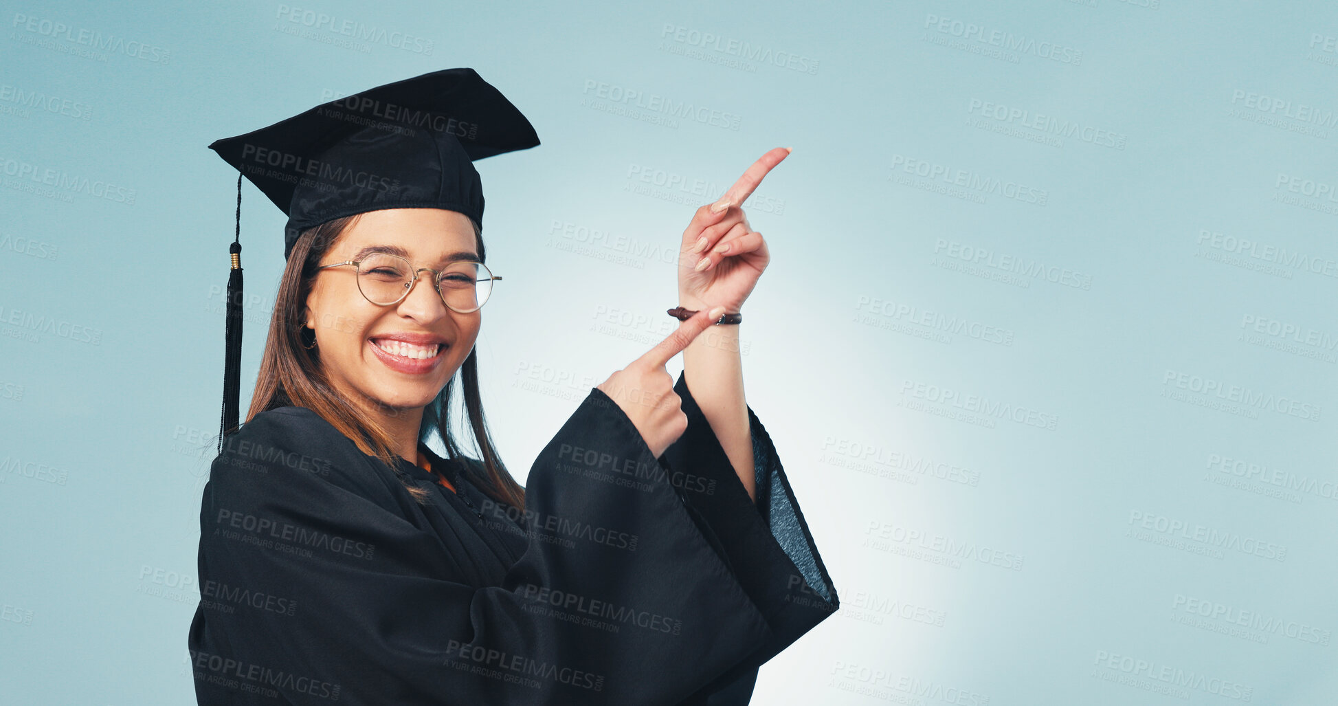 Buy stock photo Pointing, student and portrait of graduate in studio for scholarship promotion, space and pride. Graduation, announcement and university with person on blue background for study, mockup and education