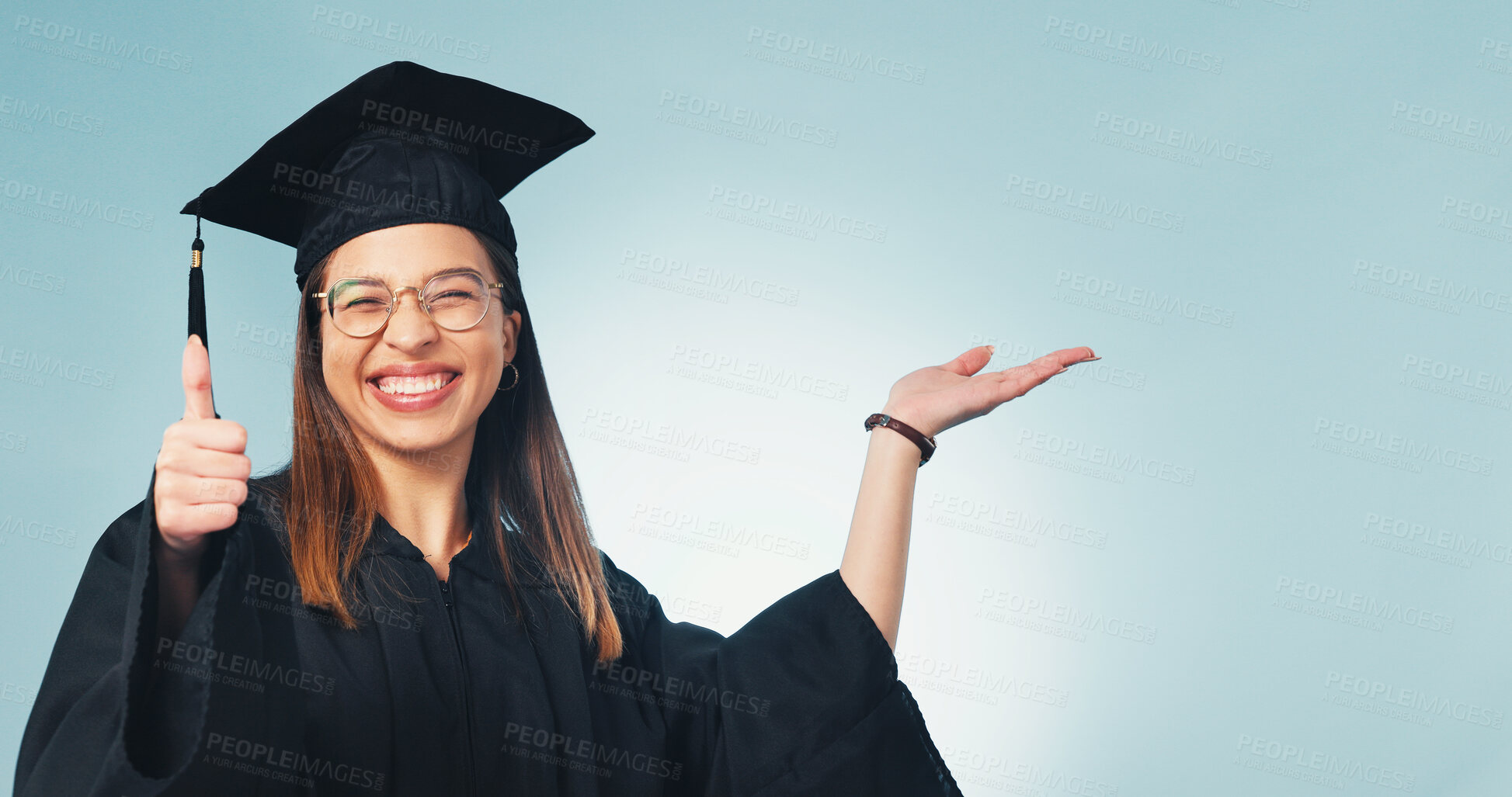 Buy stock photo Thumbs up, graduation and portrait of student in studio for scholarship promotion, space and pride. College, success and university with graduate on blue background for support, mockup and education