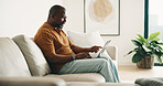 Man, reading and remote work on sofa with laptop, review draft and creativity for copywriting project. Mature, black person and freelancer in home with computer, research and copywriter for campaign.