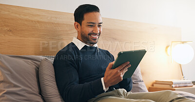 Buy stock photo Happy, man and reading in bedroom with tablet, social media and browsing website to unwind. Smile, male person and relaxing at house with tech, streaming movies and watching video for weekend break