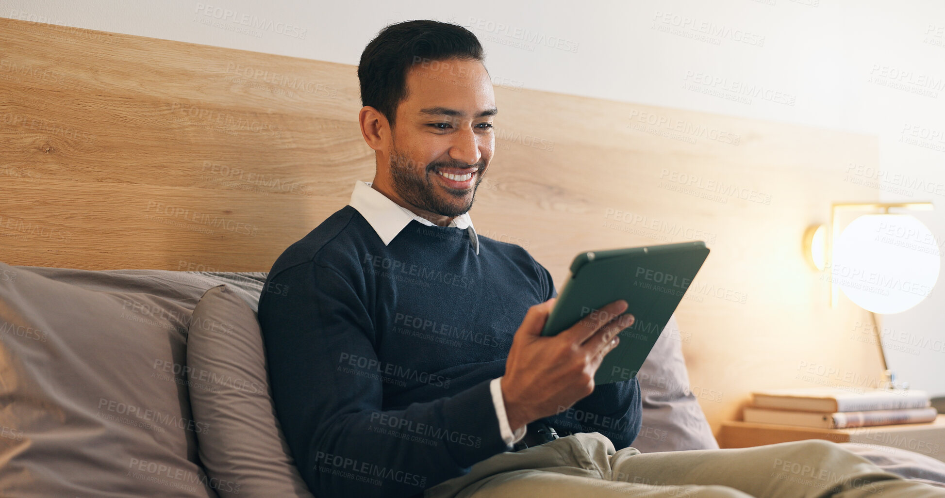 Buy stock photo Happy, man and reading in bedroom with tablet, social media and browsing website to unwind. Smile, male person and relaxing at house with tech, streaming movies and watching video for weekend break