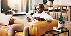 Coffee break, tablet and reading with black man on sofa for social media, online update and communication. Relax, digital tech and happy person in living room of home with ebook, app or subscription