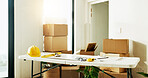Interior design, tools at table at new house for renovation, planning and boxes for relocation. Equipment, clipboard and cardboard for property construction, floor plan and maintenance of diy project