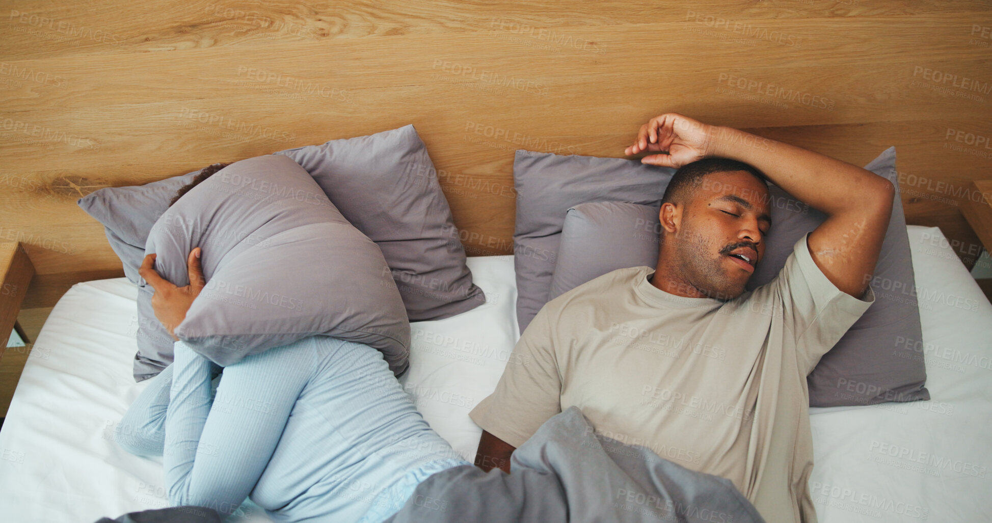 Buy stock photo Snore, couple and woman with pillow in bed for disturbance, noise and annoyed for sleep apnea. Home, above and people cover ears in bedroom with frustrated, upset and irritated for sleepless night