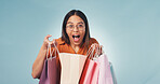 Woman, portrait and surprise with shopping bag in studio for  deal on a blue background. Excited, female person or smile with wow, gifts or presents for payment, purchase or buying spree on space