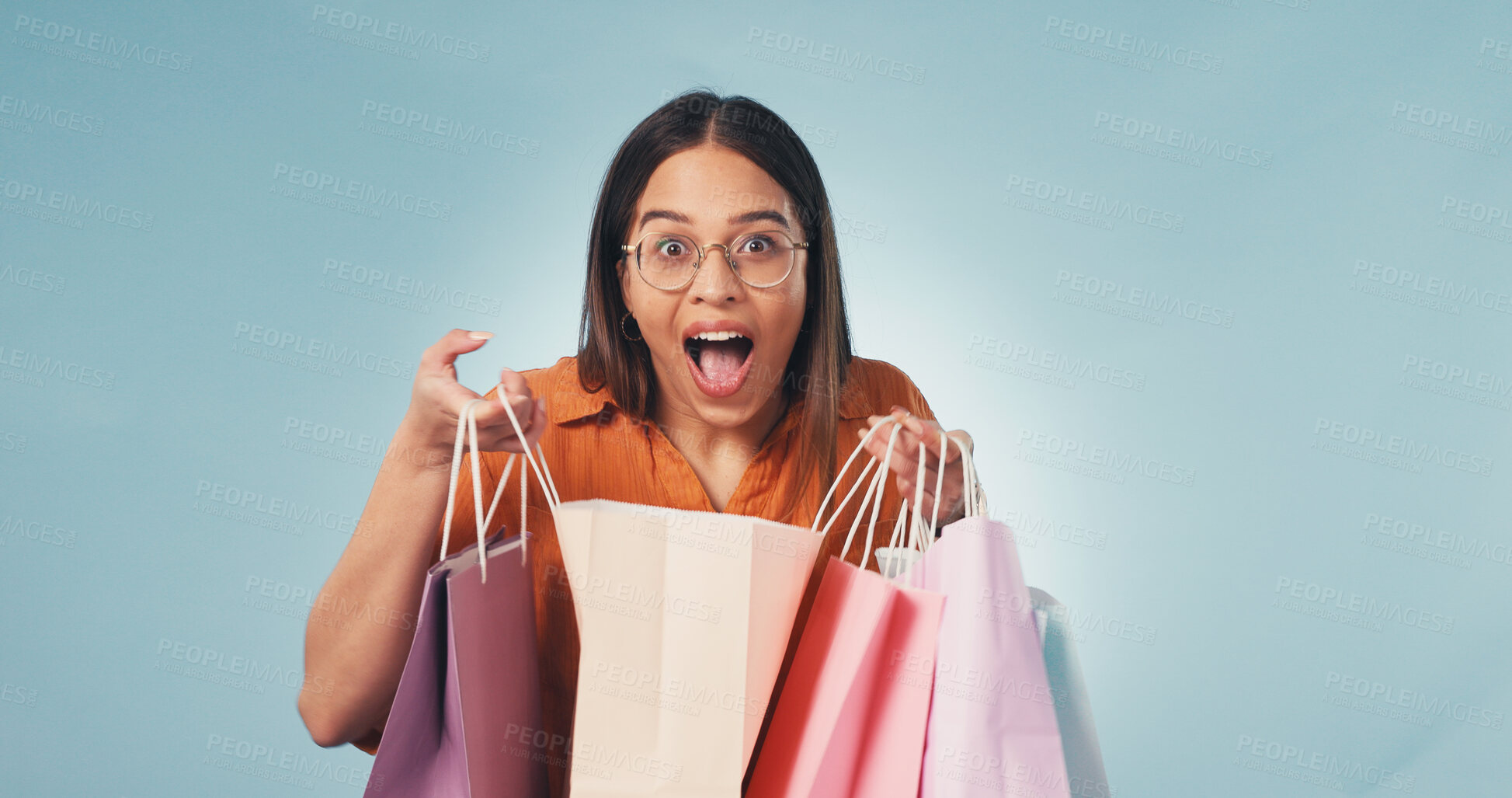 Buy stock photo Woman, portrait and surprise with shopping bag in studio for  deal on a blue background. Excited, female person or smile with wow, gifts or presents for payment, purchase or buying spree on space
