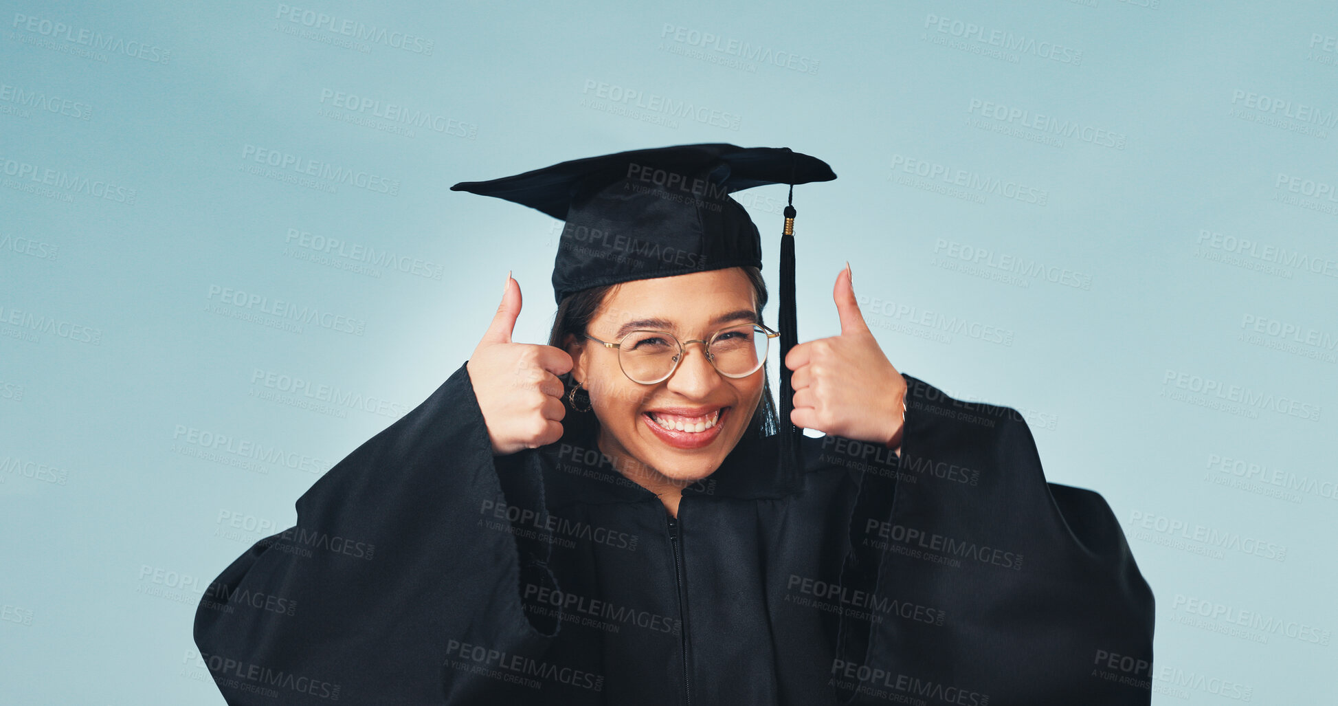 Buy stock photo Portrait, student and graduation in studio with thumbs up, celebration and thank you for success. Smile, woman or graduate with hand gesture, like university and education feedback on blue background