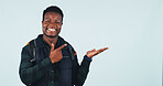 Hiking, presentation and man with smile, pointing and travel advice for adventure and recommendation. Blue background, space and black person with directions, portrait and backpacking announcement