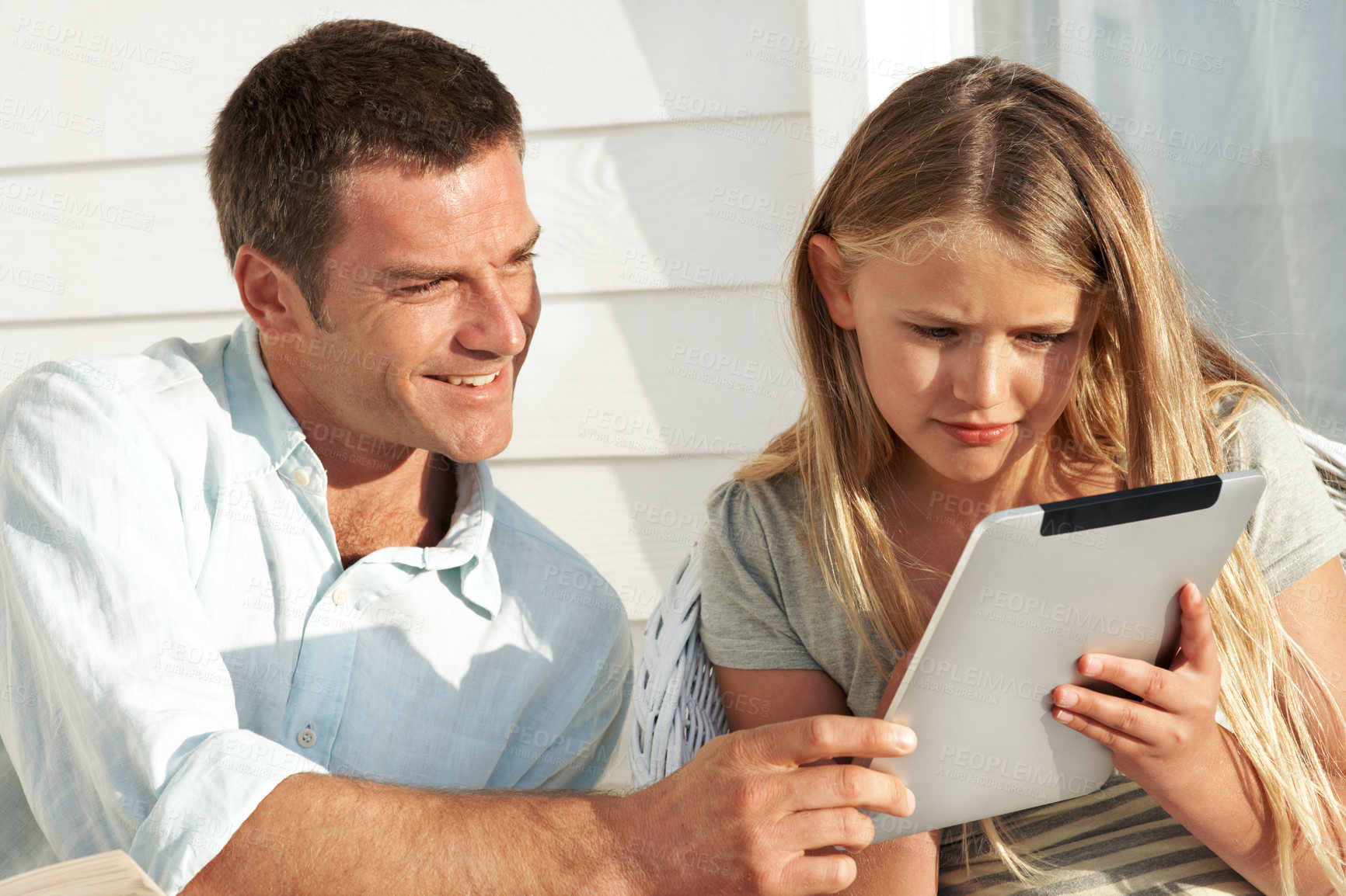 Buy stock photo Dad, child and tablet outdoor by home for watching online video, social media post and bonding. Relax, father and daughter with tech in sunshine for streaming service, weekend break and web browsing