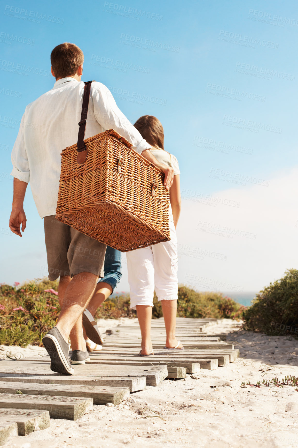 Buy stock photo Holiday, family and picnic basket on coast path for summer getaway, weekend break and support. Back, child and parents with travel adventure on boardwalk for vacation trip, outdoor and beach arrival