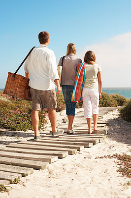 Buy stock photo Holiday, family and walk with basket at coast for summer getaway, weekend break and support. Back, child and parents with vacation adventure on boardwalk for beach picnic, bonding and outing arrival