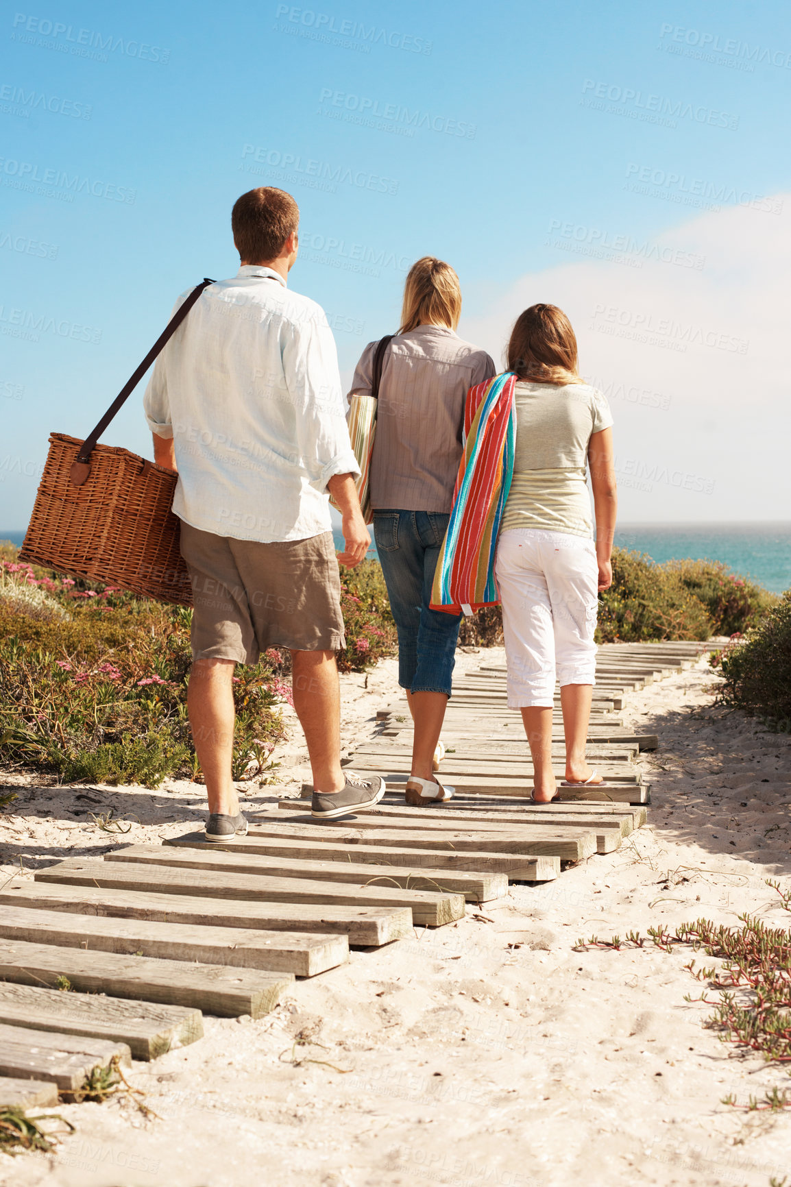Buy stock photo Holiday, family and walk with basket at coast for summer getaway, weekend break and support. Back, child and parents with vacation adventure on boardwalk for beach picnic, bonding and outing arrival
