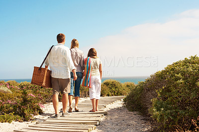 Buy stock photo Back, boardwalk and love with family at beach for summer vacation, bonding and tropical adventure. Holiday getaway, care and picnic basket with parents and child outdoor for travel on trip together