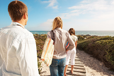 Buy stock photo Beach, path and parents with child on holiday for summer getaway, weekend break and sightseeing. Back, people and kid with family outing on boardwalk for ocean arrival, vacation support and exploring