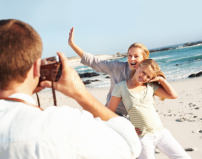 Buy stock photo Smile, photography and family at beach with camera, picture and capture moment on holiday. Happy, mother and daughter at sea with photoshoot, travel blog and bonding together on tropical vacation