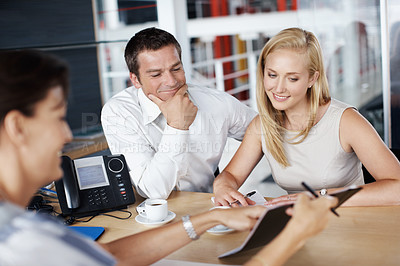 Buy stock photo A young couple and their advisor looking over the paperwork