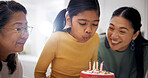 Child, family and blow candles on birthday cake at home, celebration and special day with generations. Mother, grandmother and girl with wish at party, dessert and milestone with happiness in house