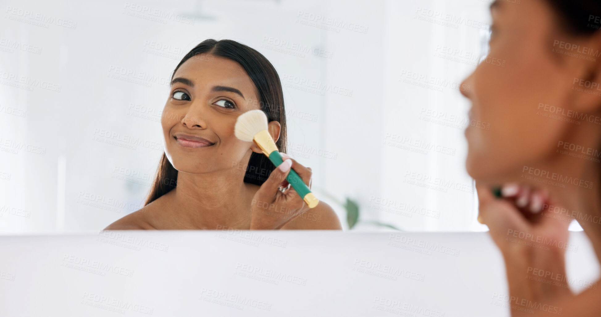 Buy stock photo Woman, makeup and brush in bathroom with mirror, morning routine or powder application for beauty. Indian person, cosmetic tools and apply foundation in home with reflection, smile and getting ready.