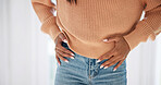 Hands, pain and woman in home with stomach, discomfort and symptoms of menstruation. Sore, female person and cramps at house with abdomen ache, constipation and inflammation for chronic endometriosis