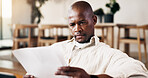 Man, reading and paperwork in home with financial planning, review utility bills and wealth management. Black person, check document and budget in lounge with mortgage bond, household cost or expense