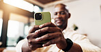 Hands, phone and man in home with mobile connection for social media, messaging app and search. Black person, technology and scroll online in lounge to relax, networking and notification on sofa