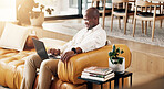 Freelance, laptop and smile with black man on sofa in home living room for planning or research. Computer, reading and remote work with happy person in apartment for feedback, report or review