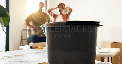 Buy stock photo Bucket, leaking and couple at new house with stress, roof damage and issues of unexpected repairs. Container, people and dripping water in home with renovation failure, plumbing issue and maintenance