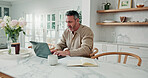 Mature, finance and man with laptop for budget planning, report or home expenses in kitchen. Male person, accounting and typing on computer with book for financial review or tax assessment in house