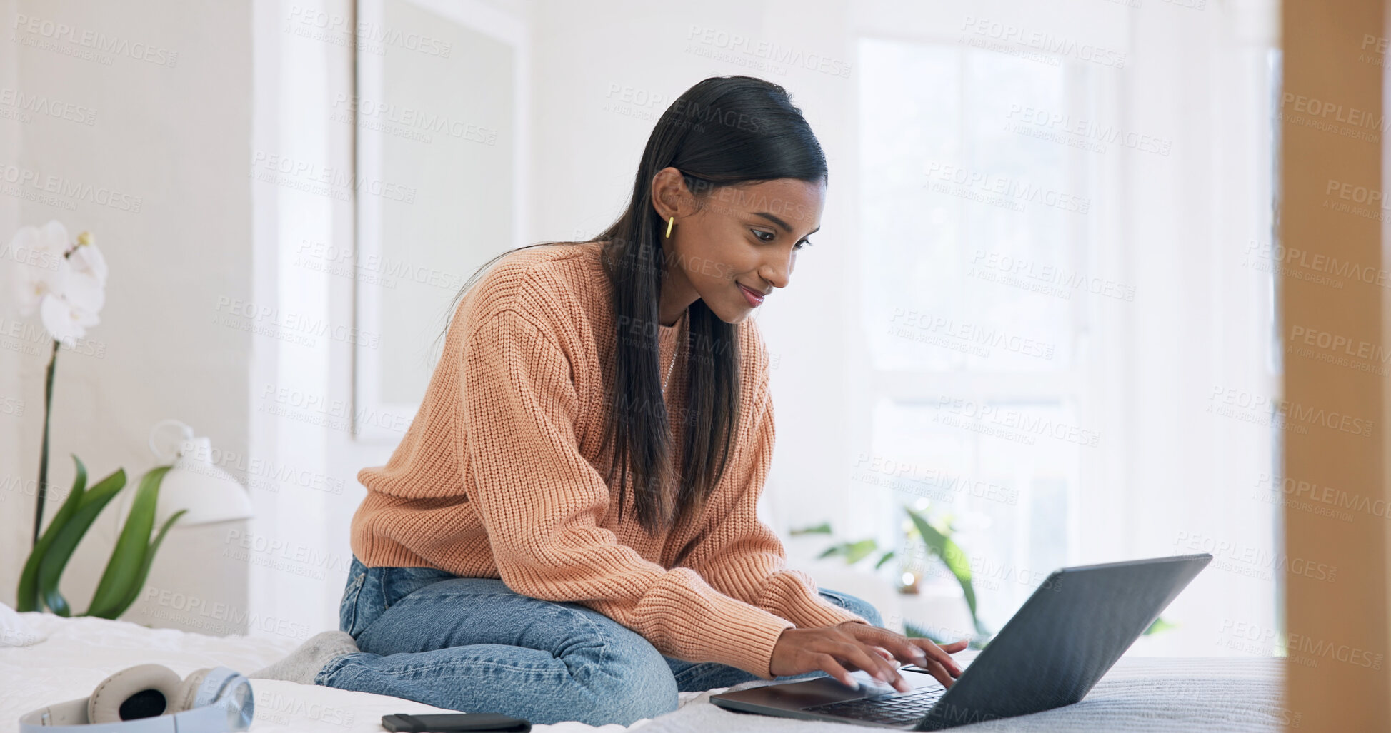 Buy stock photo Creative, freelancer and happy woman with laptop on bed, typing and video editing on web in bedroom. Editor, home and Indian person with tech, remote work and content creation on social media app