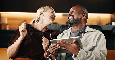 Buy stock photo Interracial couple, tablet and laugh with earphones for movie, mobile app and conversation in home. Mature people, chat and smile for streaming, subscription and tech for humor on social media