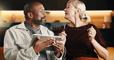 Buy stock photo Interracial couple, tablet and relax with earphones for streaming, mobile app and conversation in home. Mature people, chat and smile for movie, subscription and tech for humor on social media