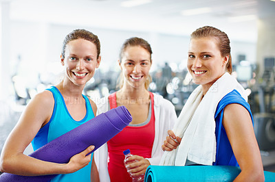 Buy stock photo Portrait of three young women with yoga mats standing in a gym