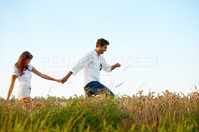 Buy stock photo Couple, holding hands and walking in meadow with blue sky, partner and support with care in nature. People, marriage and romantic stroll for healthy relationship, bonding together and space for love