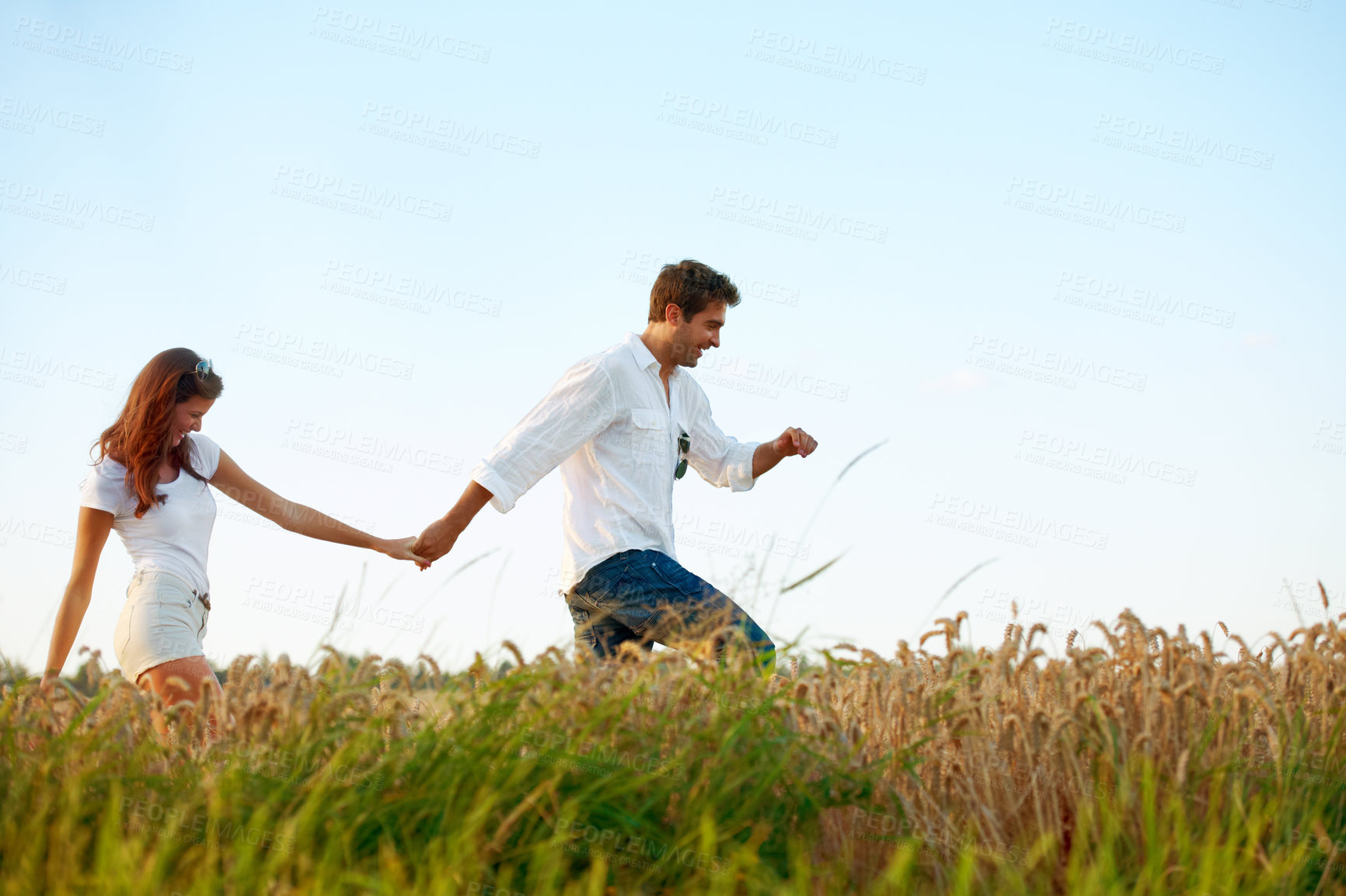 Buy stock photo Couple, holding hands and walking in meadow with blue sky, partner and support with care in nature. People, marriage and romantic stroll for healthy relationship, bonding together and space for love