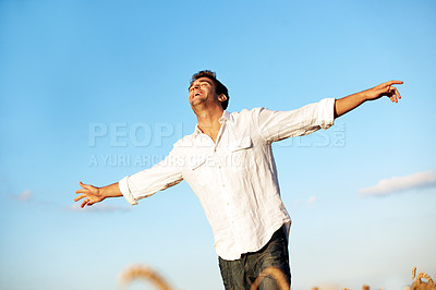 Buy stock photo Freedom, happy and man in countryside with blue sky, gratitude and open arms for peace on weekend. Field, smile and person with joy, wellness and relax for holiday, break and adventure outdoor