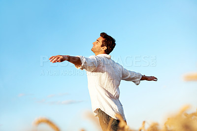 Buy stock photo Happy, freedom and man in field for gratitude, thinking and fresh air for wellness on weekend. Outdoor, smile and person for reflection, thoughtful and calm for holiday, break and relax with blue sky