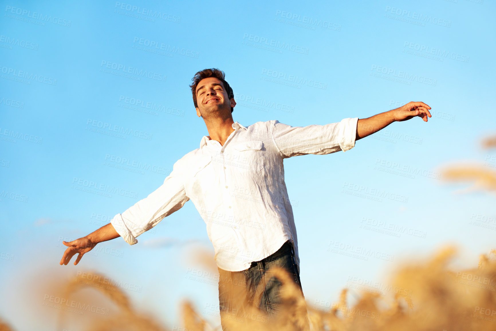 Buy stock photo Happy, freedom and man in field with open arms, gratitude and fresh air for wellness on weekend. Blue sky, smile and person with reflection for carefree, peace and calm for holiday, vacation or break