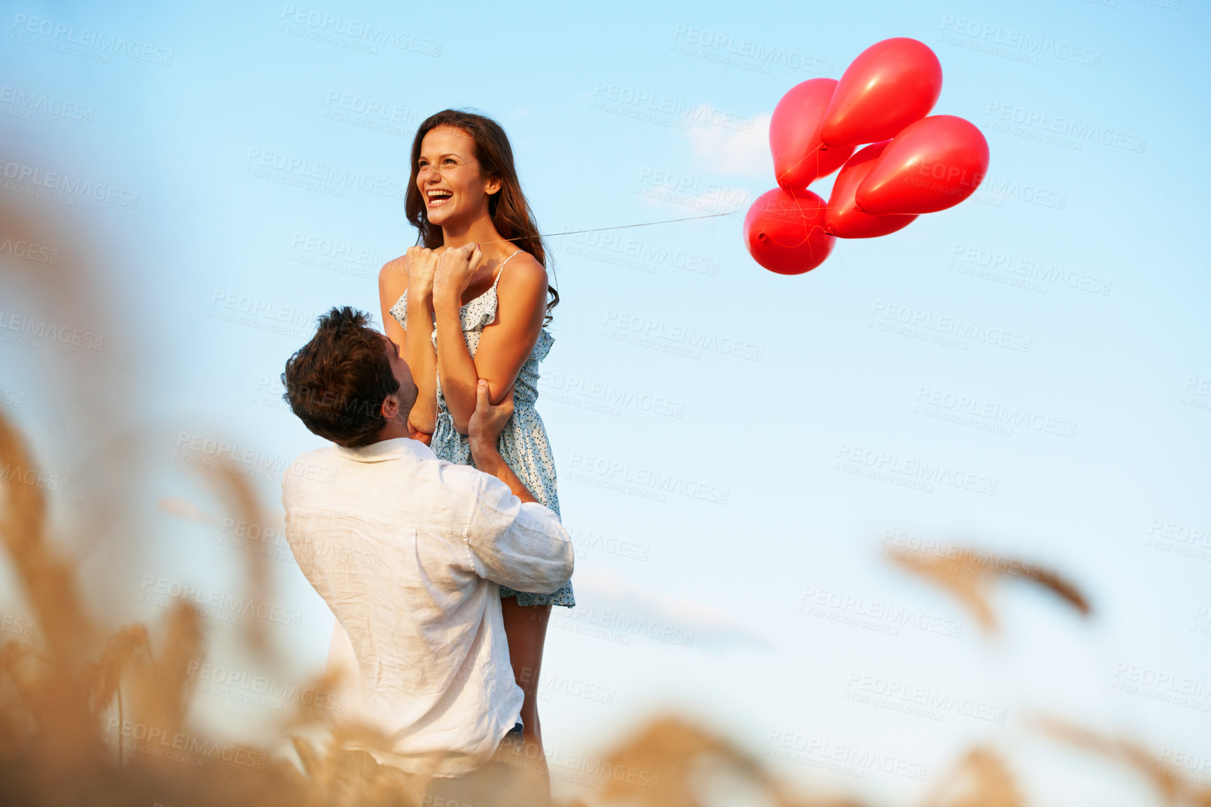 Buy stock photo Excited, couple and celebration outdoor with balloons, support and romantic gesture for anniversary. Space, married people and lift wife in countryside with relationship commitment, love and loyalty.