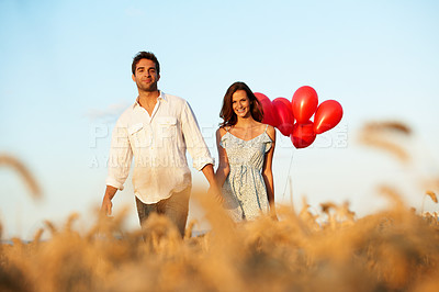 Buy stock photo Portrait, couple and holding hands in countryside with balloons, walk and bonding for anniversary. Happy, married people and romantic gesture in wheat field with relationship, love and commitment.